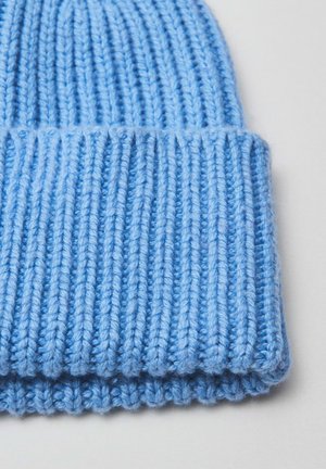 Bonnet tricoté bleu avec une texture côtelée, comportant un revers. Fabriqué en fil doux avec des détails de couture visibles.