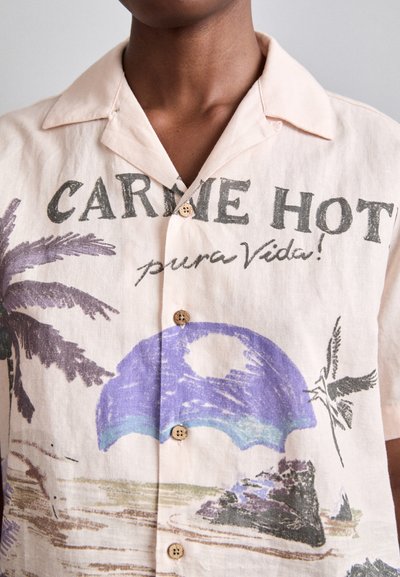 Short-sleeve, light pink button-up shirt with a tropical design featuring palm trees and an umbrella in purple, green, and brown tones.