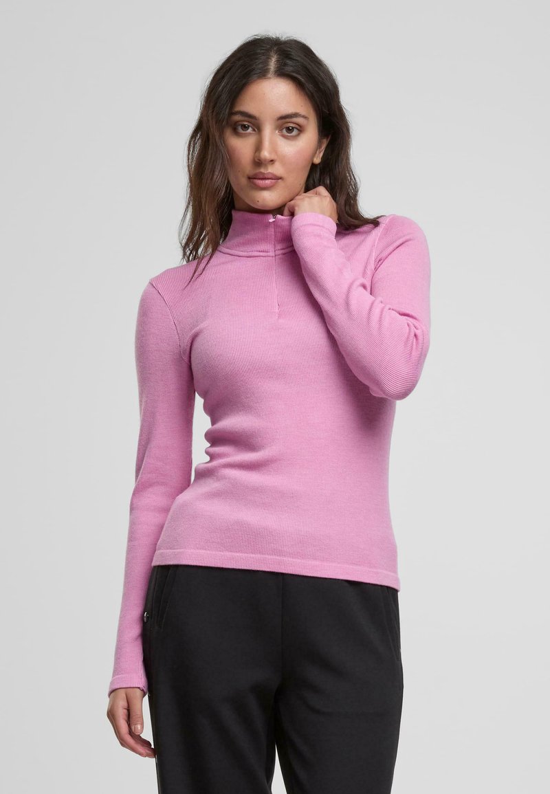 Langärmliger Pullover mit Reißverschlusskragen aus weichem, pinkem Stoff mit geripptem Textur. Figurnahes Design mit glatter Oberfläche und minimalistischem Stil.
