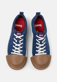Zapatillas de ante azul con cordones blancos y punteras de goma marrón, con el logo "CAMPER" en la plantilla y en la etiqueta del talón de color rojo.