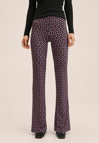 Spodnie w kształcie dzwonów w fioletowym materiale, z floralnym wzorem czarnych i różowych kwiatów. Średnio wysoki stan i miękka, gładka tekstura.