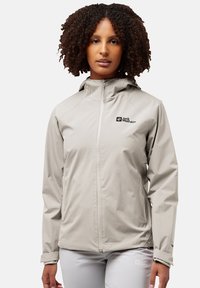 Lichtgrijze, waterdichte jas met een aansluitend ontwerp, een rits aan de voorkant en een verstelbare capuchon. Heeft een logo op de borst en detail op de manchet.