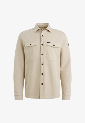 Beige nappipaita, jossa on teksturoitu neulekangas, kaksi rintataskua, mustat nepparit ja klassinen kaulus.