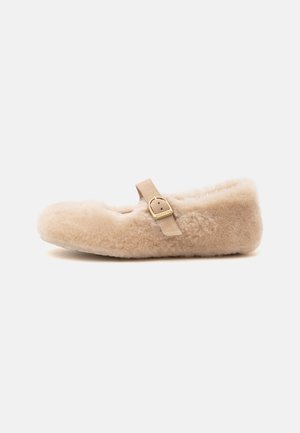 Beige fluffy Mary Jane tøfler med en enkelt læderrem og guldlås, flad sål, sidevisning mod hvid baggrund.