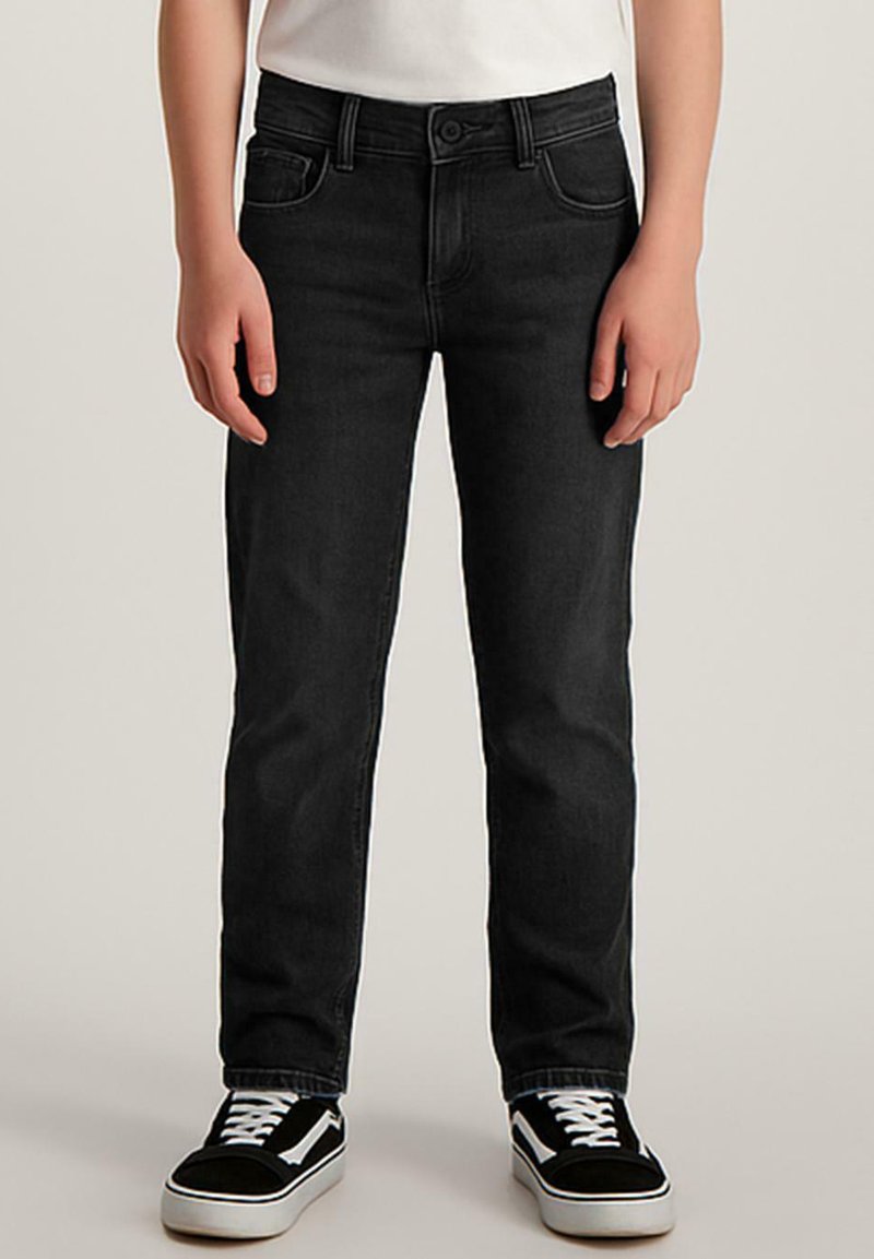 Zwarte denim jeans met een rechtvallende pasvorm, vijf zakken en contrasterende stiksels. Gepaard met zwart-witte sneakers.