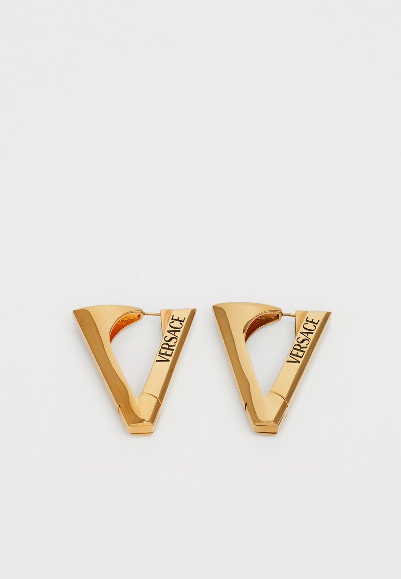 Guldfärgade metallörhängen formade som ett "V", med graverad "Versace"-text och en slät, polerad yta.