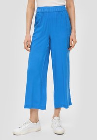 Blauwe broek met wijde pijpen en een elastische tailleband. Gemaakt van een lichtgewicht stof, met een soepele textuur en een relaxte pasvorm. Gepaard met witte sneakers.