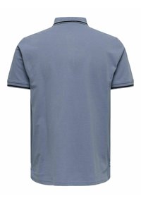 Polo de color azul claro hecho de algodón. Presenta un cuello plano con acentos negros y mangas cortas. Textura suave, diseño sencillo.