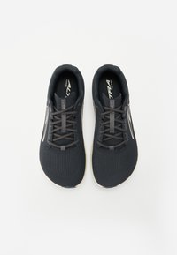 Chaussures de sport noires avec une tige en tricot texturé, des lacets gris et une semelle beige. Présentent un logo sur la languette et sur les côtés.