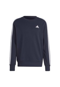 Tamno plavi dukserica s dugim rukavima, okruglim izrezom i bijelim trostrukim trakama duž ramena. Na prsima se nalazi mali bijeli logo.