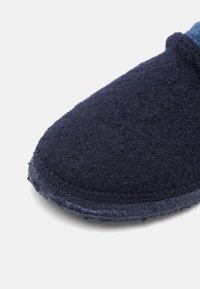 Navy felt slipper with a soft texture, rounded toe, and a dark rubber sole. Features contrasting stitching along the edge for added durability.
