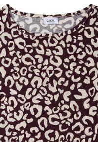 Top de cuello redondo con estampado de leopardo en blanco y marrón oscuro y etiqueta de la marca "CECIL" en el cuello.