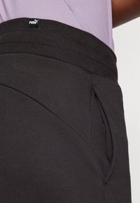 Zwarte joggerbroek met een geribbelde tailleband, voorzien van een zijzak en het Puma-logo op de tailleband. Gladde stofstructuur.