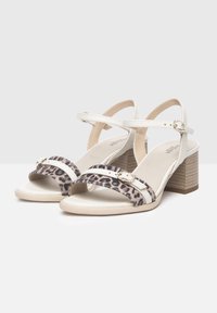 Sandali con tacco alto bianchi e con stampa leopardata con fasce incrociate, caratterizzati da piccoli dettagli in tono oro e un tacco a blocco texturizzato.