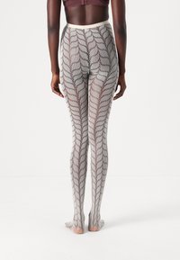 Sheer, patterned tights with a zigzag design in gray and black, featuring a soft waistband and open foot at the bottom.