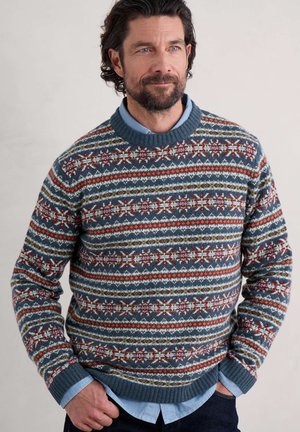 Knitted sweater in blue with patterned stripes featuring red, green, and white accents. Ribbed neckline and cuffs. Casual fit.