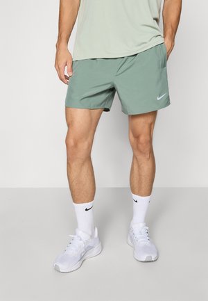 Moške športne kratke hlače Nike v svetlo zeleni barvi, narejene iz lahkega materiala. Zasnovane so s stransko žepom in belim logotipom Nike. Uporabljene z belimi športnimi copati in nogavicami.