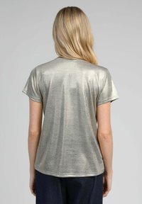 T-shirt en or métallique à manches courtes avec une texture lisse et un col rond, avec des coutures détaillées et une coupe décontractée, vu de dos.