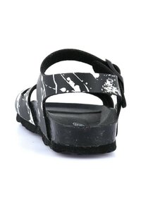 Sandali neri con motivo a macchie bianche, molteplici cinturini e una fibbia robusta. Presentano una suola testurizzata e un plantare sagomato.