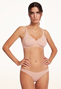 Reggiseno color nudo con texture liscia, scollo a V e spalline sottili regolabili; slip bikini abbinati con finitura senza cuciture.