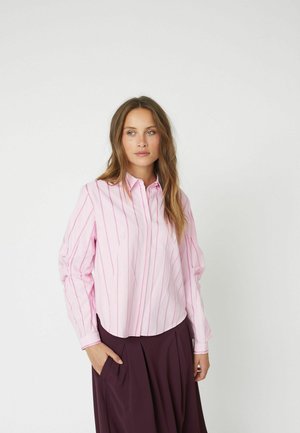 Light pink button-up shirt with vertical darker pink stripes, a collar, and long sleeves, paired with a dark pleated skirt.