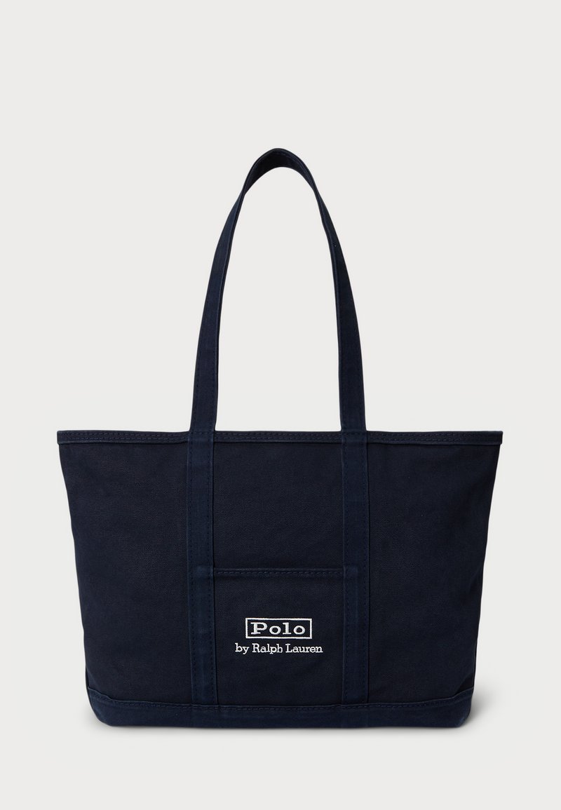 Ναυτικό μπλε καμβάς τσάντα tote με δύο ιμάντες στον ώμο, μπροστινή τσέπη και λευκό λογότυπο "Polo by Ralph Lauren" ραμμένο μπροστά.