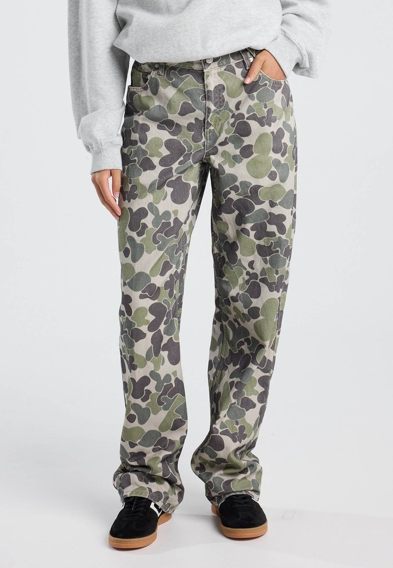 Pantalons cargo camouflage présentant un motif de formes vert foncé et gris sur un fond clair, fabriqués à partir d'un tissu robuste, avec une coupe décontractée.