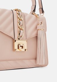 Světle růžová prošívaná kožená kabelka s pozlaceným řetězovým popruhem, zlatým zapínáním a copánkovou střapcovou detaily.