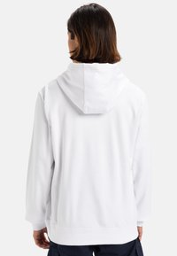 Sudadera blanca con una textura suave, con capucha en la parte posterior del cuello, mangas largas y puños y dobladillo acanalados.