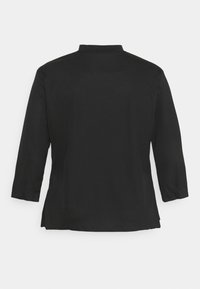 Svart, ribbade långärmade tröja med krage och sidofickor. Baksidan har en slät yta och en avslappnad silhuett.