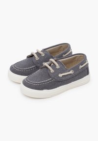 Graue Segelschuhe aus Canvas mit weißen Gummisohlen, ausgestattet mit cremefarbenen Schnürsenkeln und Nähten, runder Zehenpartie und niedrigem Profil.