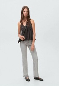 Svart ärmlös topp med rynkad midja, grå utsvängda jeans och svarta lägenheter med silvernitar. Enkla linjer och avslappnad passform.