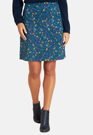 Floral A-Linie-Rock in Petrol mit lila und grünen Mustern. Kombiniert mit dunklen Schnür-Stiefeln. Weicher Stoff mit glatter Textur.