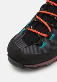 Zwarte en grijze wandelschoen met een gestructureerde stof, oranje en gele veters, turquoise accenten en een gestreepte rubberen zool.