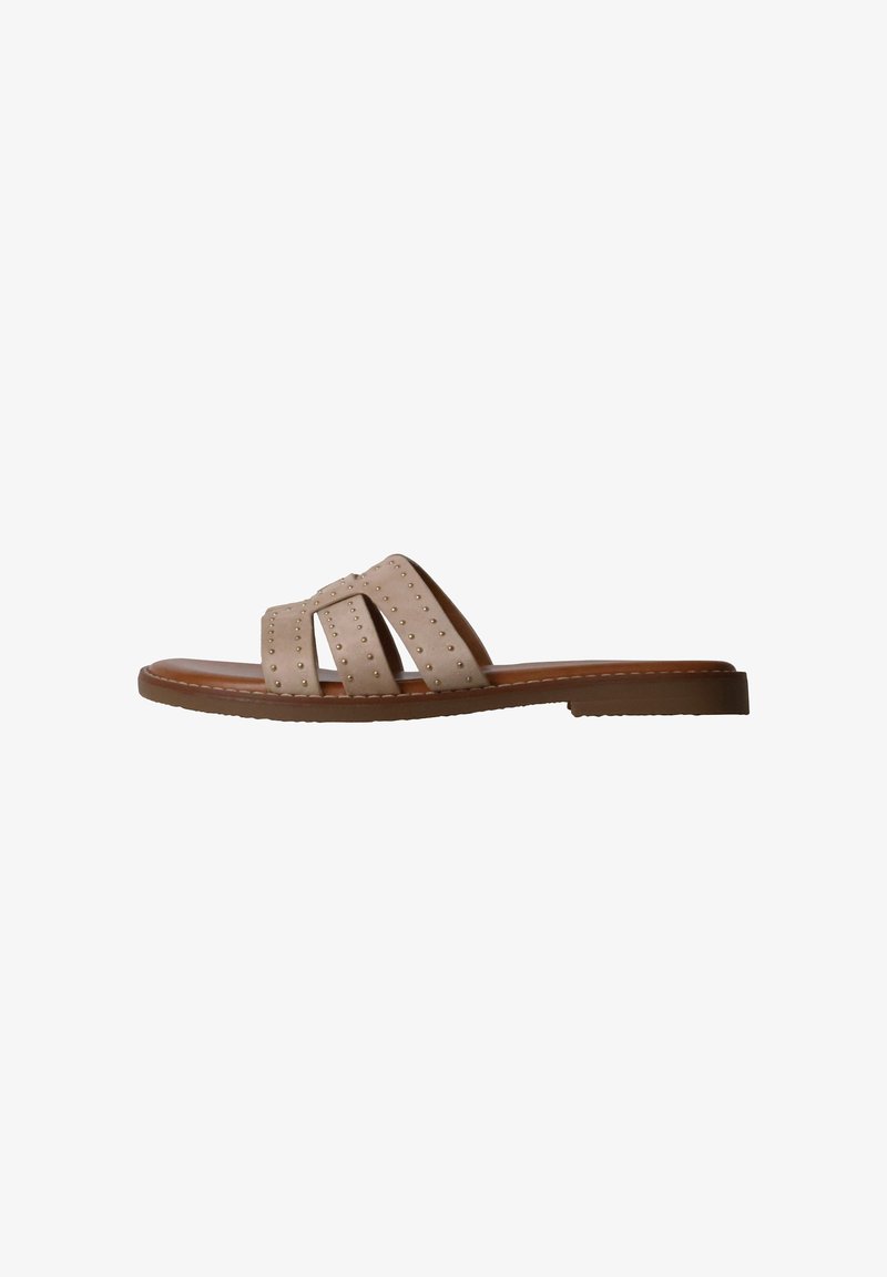 Sandale plate beige avec trois brides cloutées et une semelle marron vue de côté sur fond blanc.