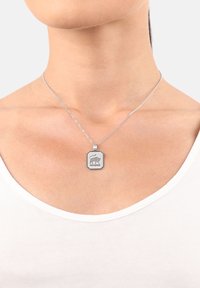 Collana d'argento con un pendente ottagonale che presenta un design animale inciso. La catena è composta da piccoli anelli tondi.