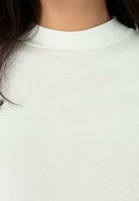 Långärmad, tight topp i ljus mintgrön. Tillverkad av ett ribbat tyg med hög hals och jämn textur. Inga synliga mönster eller detaljer.