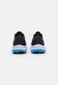 Scarpe sportive nere con tomaia in rete, dotate di una suola blu e bianca. Accenti gialli sui lati e parte posteriore testurizzata per la stabilità.