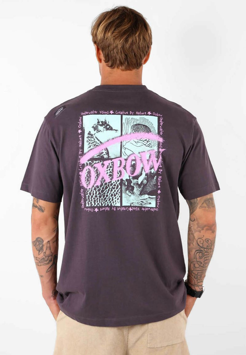 T-shirt en coton gris avec un design graphique multicolore dans le dos, comprenant des illustrations et du texte encadrés dans des couleurs contrastées.