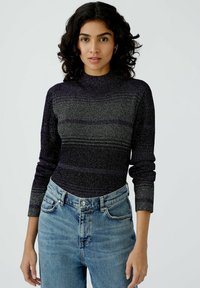 Gestrickter Langarm-Top in Dunkelpurple mit helleren horizontalen Streifen. Hoher Kragen und enganliegendes Design, kombiniert mit hellblauen High-Waist-Jeans.