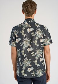 Camisa de manga corta en tejido oscuro con un patrón floral que presenta flores de colores claros y follaje verde; diseño casual con cuello.