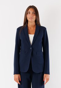 Blazer blu navy con un bottone singolo, rever a punte e due tasche anteriori, realizzato in tessuto liscio. Design semplice e su misura con maniche lunghe.
