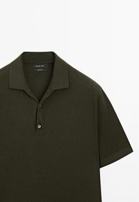 Polo shirt corto a maniche corte verde scuro realizzato in cotone con una texture morbida, dotato di un colletto classico, bottoni a due sull'apertura e dettagli di cucitura discreti.