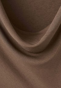 Tissu doux marron clair avec des plis lisses et fluides ainsi qu'une texture fine et détaillée visible sous un éclairage uniforme.