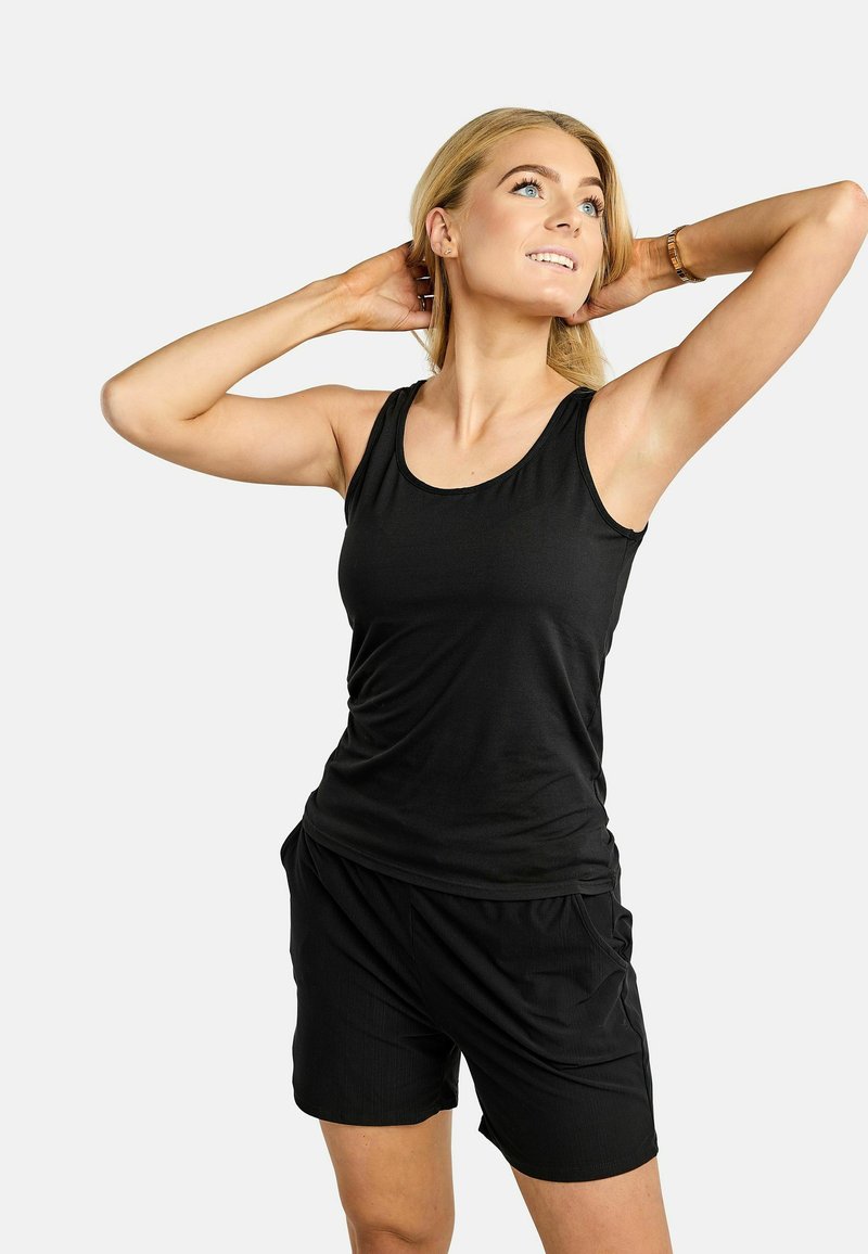 Débardeur noir sans manches avec encolure arrondie et coupe décontractée, assorti à un short noir avec poches latérales et texture douce.