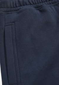 Laivastonsiniset collegehousut pehmeästä, teksturoidusta kankaasta, joissa on joustava vyötärönauha ja sivutasku, jossa on litteä aukko.