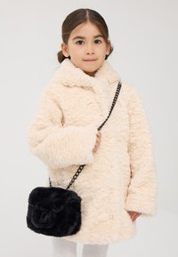 Kremowy płaszcz z sztucznego futra z szerokim kołnierzem i długimi rękawami; czarna torebka z sztucznego futra na ramię z łańcuszkowym paskiem. Miękka tekstura i zaokrąglony kształt.