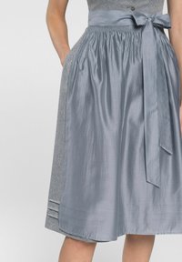 Ein grauer Rock mit satinartigem Finish, seitlichen Taschen und einem passenden Bindegürtel in der Taille, sowie einem strukturierten Stoffpaneel auf einer Seite.
