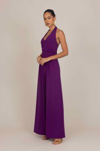 Giromone viola con scollatura a halter, corpetto aderente, gambe ampie e texture morbida. Presenta un design arricciato in vita. Accessori dorati.
