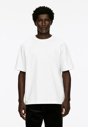 White short-sleeve t-shirt made of cotton, featuring a crew neck and relaxed fit. Smooth texture with no visible patterns or hardware details.